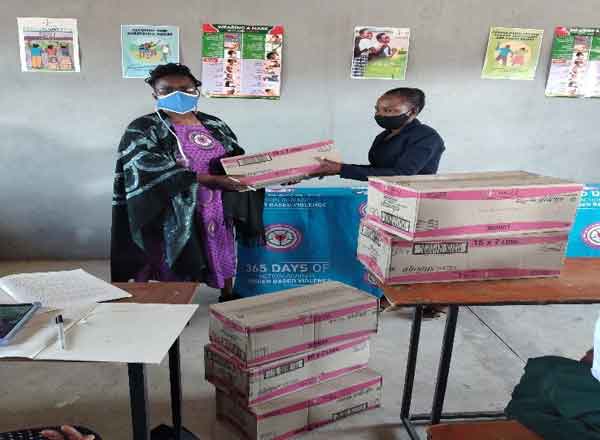 Rev E Moyo handling a box of sanitary pads to Majijimba Secondary school teacher